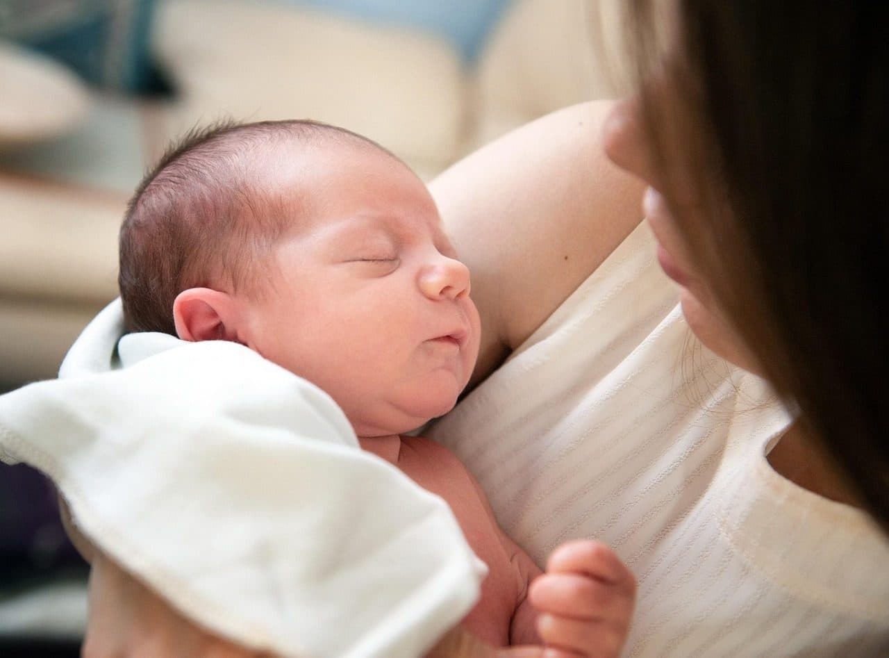 Una mamá mirando a su bebé recién nacido dormido