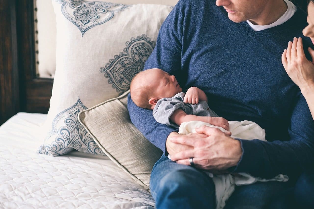 Un papá en el sillón con su bebé recién nacido en brazos