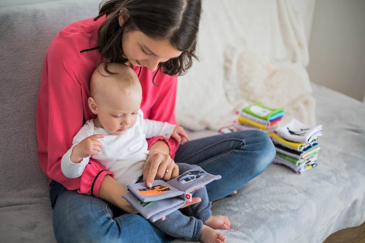 Una mamá en el sillón mirando un libro con su bebé