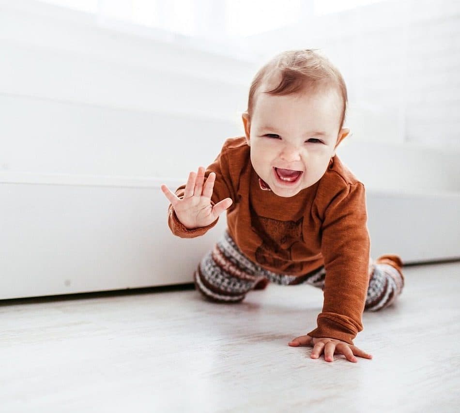 Una beba de unos ocho meses gateando y riéndose